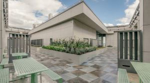 Light coloured aluminium metal planters on a modern commercial terrace in the UK with architectural paving and planting