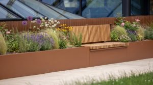 Corten steel planter with integrated timber bench seating and mixed flowering plants on a modern UK rooftop terrace