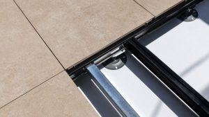 Metal planter paving subframe edge detail showing terrace slabs supported by aluminium rails and adjustable pedestal bases for a raised outdoor system.