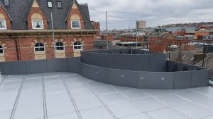 Metal planter system on a rooftop terrace with curved grey planter walls installed around a raised outdoor space in a modern UK urban setting.