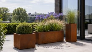 Corten metal planter terrace planters with flowers, grasses and shrubs beside a modern glass doorway.